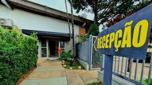 Uma área de recepção com uma placa que diz "RECEPCAO" em letras amarelas sobre fundo azul.