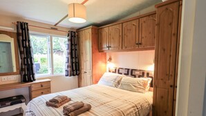 Ein Schlafzimmer mit einem Bett, einem Schreibtisch, einem Spiegel und Holzschränken.