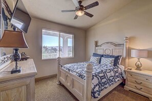 A bedroom with a bed, bedside tables, a ceiling fan, and a window.