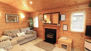 A cozy cabin interior with a fireplace, wooden walls, a sofa, and a small table. - The Fold (Keswick)