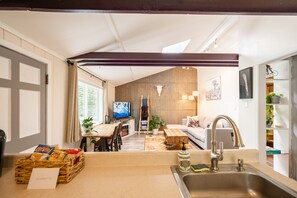 Una cucina moderna con un tavolo da pranzo in legno, un lavandino e una televisione sullo sfondo.