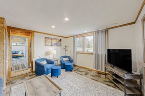 Relax in this stylish living room with a large flat-screen TV, comfortable sofa, and a side table with a lamp.