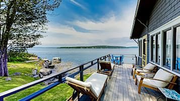 Relax on the deck with a view of the lake, surrounded by lounge chairs and a small table.