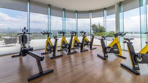 A gym with stationary bikes arranged in a row, large windows, and a view of the outdoors. - Amazing Jewel Beach front Condo with great views (Bucerias/ Nuevo Vallarta)