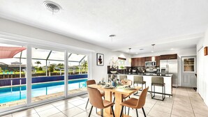 Cocina moderna con una isla central, ventanas amplias y vista a una piscina.