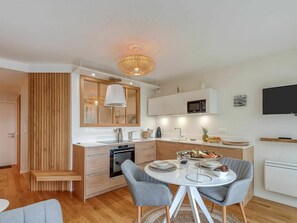 Une cuisine moderne avec un coin repas, des éléments décoratifs en bois et un téléviseur à écran plat.