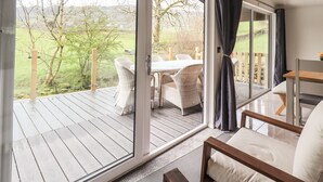 Une pièce dotée d’une grande porte-fenêtre coulissante qui donne sur une terrasse extérieure avec une table et des chaises.