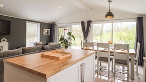 Une cuisine moderne avec un îlot central en bois, des meubles blancs et un coin repas comprenant des chaises et une table, le tout dans des tons blancs.