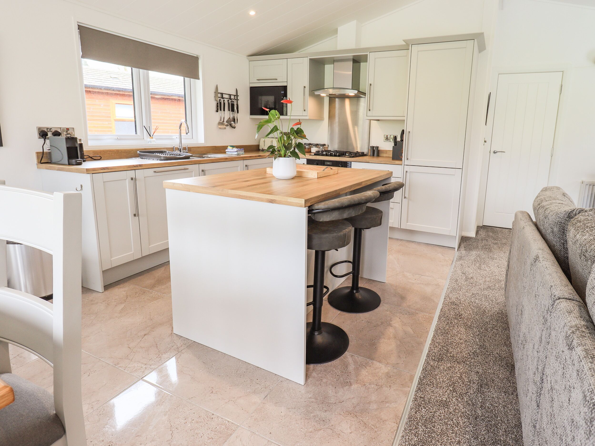 A modern kitchen with white cabinets, a wooden island, and a built-in stove.