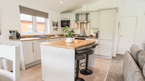 Une cuisine moderne avec des armoires blanches, un îlot central en bois et une cuisinière intégrée.