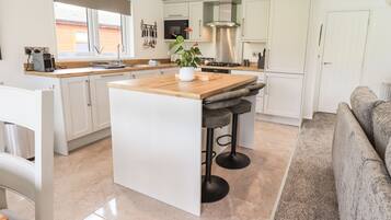 A modern kitchen with white cabinets, a wooden island, and a built-in stove.