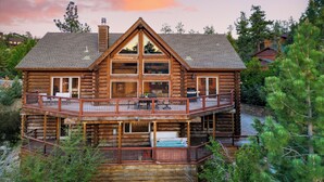 A log cabin with a balcony and a hot tub.