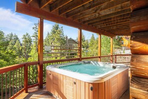 A wooden deck with a hot tub, wooden railings, and a view of a house and trees. - 0.5mi to the Lake, Deck w/ Views, Poker Table | Eagle Ridge Retreat by AvantStay (Big Bear Lake)