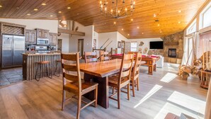 Una cocina amplia con armarios de madera, una isla central con taburetes y un comedor con una gran mesa y sillas de madera.