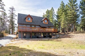 A large two-story lodge with a balcony, surrounded by trees.