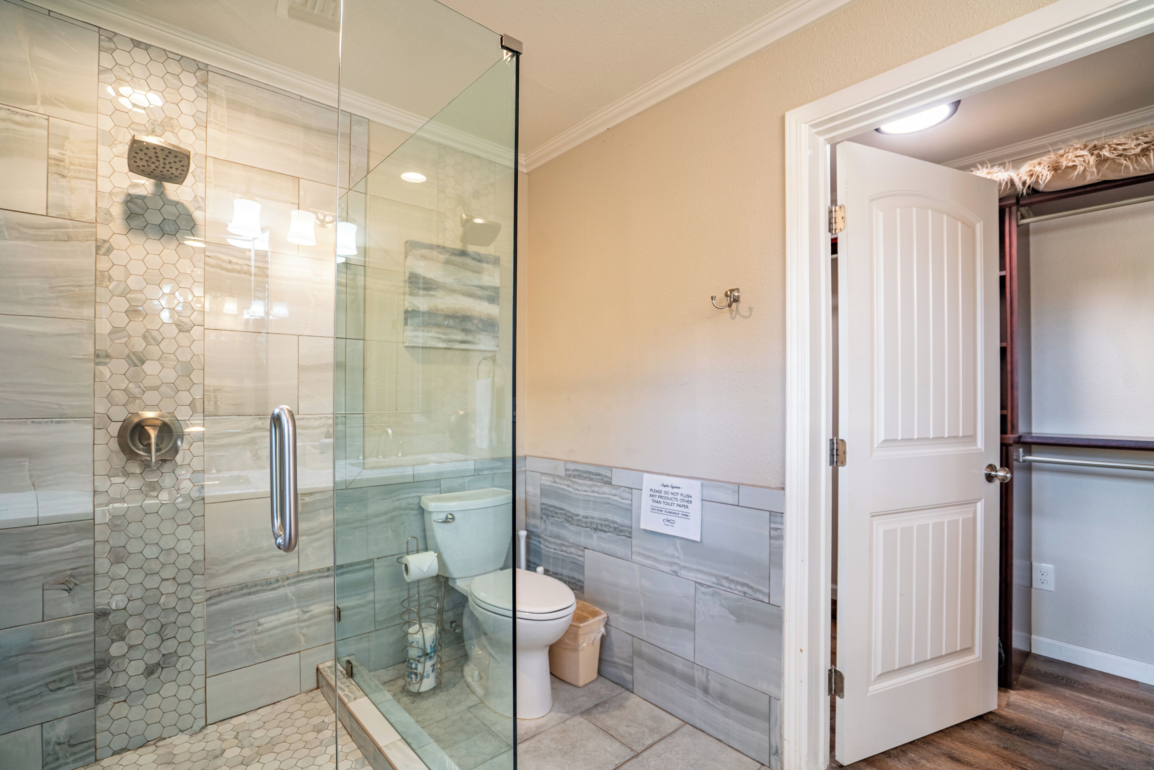 A bathroom with a glass-enclosed shower, a toilet, and a sink.