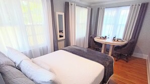 Een hotelkamer met een groot bed, een klein tafeltje met een stoel en een raam met gordijnen.