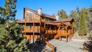 A large wooden lodge with multiple balconies and a stone chimney.