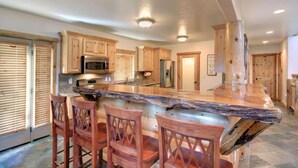 A kitchen with wooden cabinets, a granite countertop, and a central island with bar stools.