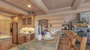 Une cuisine spacieuse avec des meubles en bois, une longue table à manger et une cheminée en pierre.