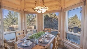 Une salle à manger en bois avec une table ronde dressée pour quatre personnes, entourée de chaises.
