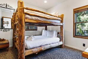 Ein Etagenbett mit natürlicher Holzrahmen, weißer Bettwäsche und einem Leopardenmuster-Teppich.