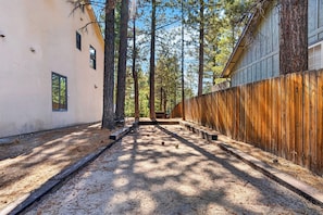A narrow alleyway with a wooden fence on one side and a building on the other. - Walk to Lake | 6BR Cabin w/ Game Room, Hot Tub | Big Bear Castle (Big Bear Lake)