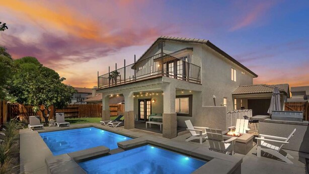 A two-story house with a balcony, a swimming pool, and outdoor seating.