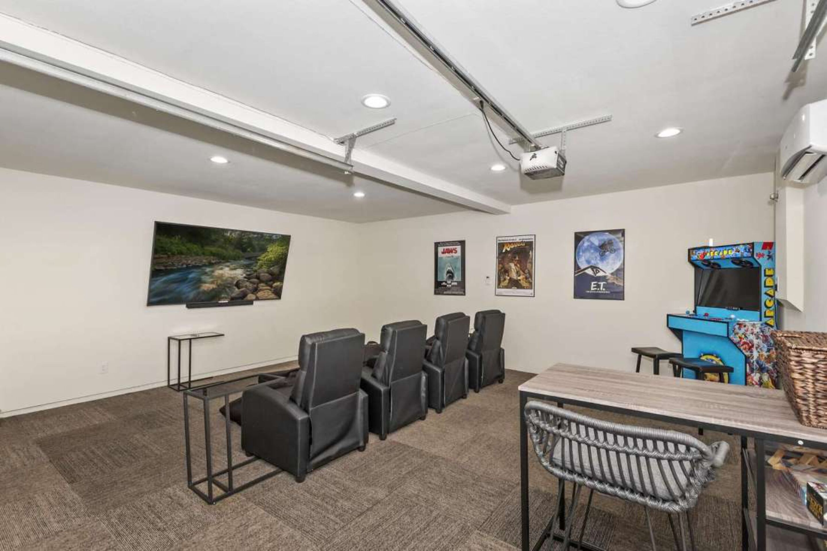 Uma sala de conferências com projetor, mesa, cadeiras e parede com cartazes.