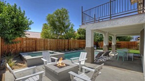 A backyard with a pool, outdoor seating, and a covered patio area.
