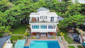 Une maison à deux étages avec une piscine, entourée d’une végétation luxuriante.