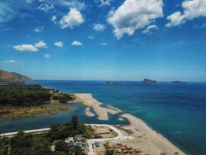 A coastal resort with a sandy beach, clear blue waters, and a small marina. - Youhan Beach Resort powered by Cocotel (San Antonio)