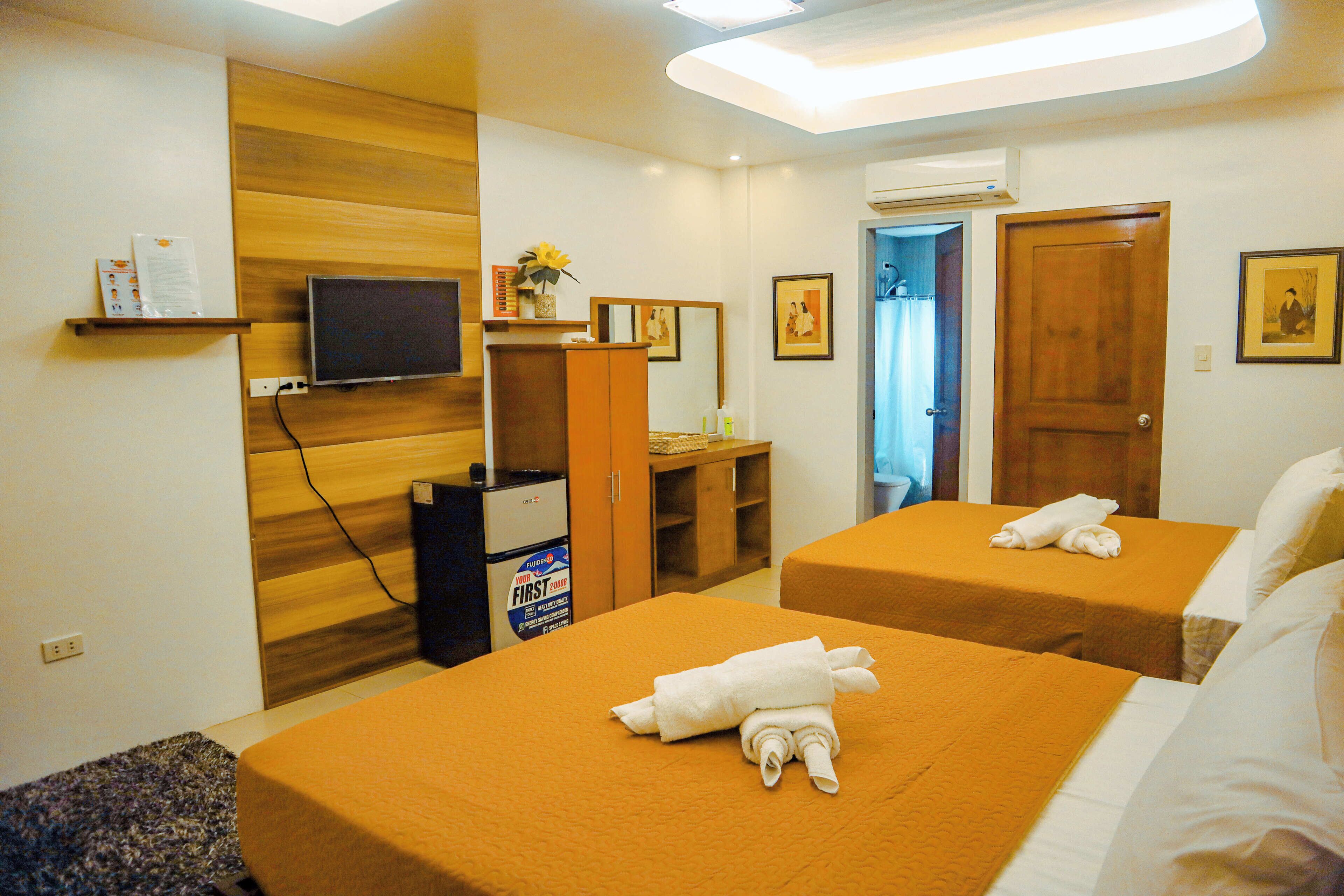 Una habitación de hotel con dos camas, televisión, escritorio y espejo.