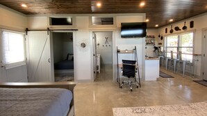 A spacious room with a bed, a desk, a TV, and a kitchenette.