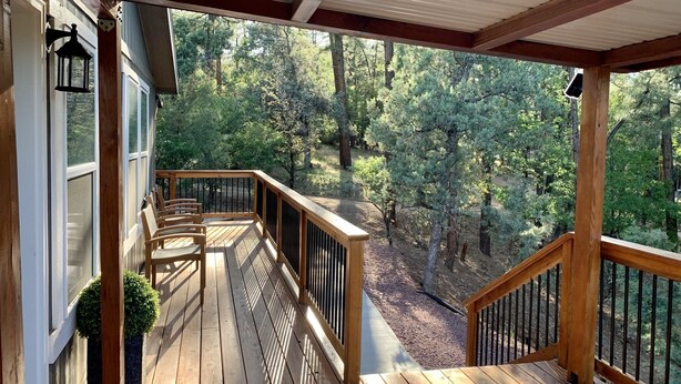 A wooden deck with a railing, overlooking a forested area. - Entire Home! Big Style, Big Views, Great Location! (Pine)
