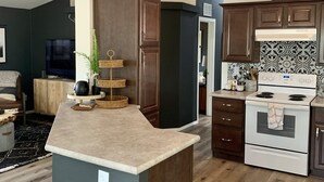 A modern kitchen with dark cabinetry, a central island, and a built-in stove. - Entire Home! Big Style, Big Views, Great Location! (Pine)