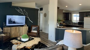 A modern living room with a television, a ceiling fan, a coffee table, and a comfortable seating area. - Entire Home! Big Style, Big Views, Great Location! (Pine)