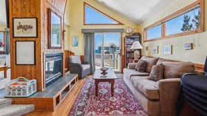 A spacious living room with a large window, a wooden ceiling, and a cozy seating area.