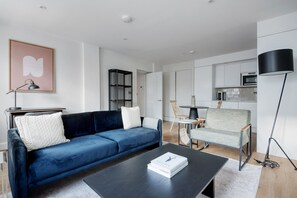 A modern living room with a dark blue sofa, a coffee table, and a bookshelf.