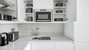 A modern kitchen with white cabinets, a built-in microwave, stainless steel appliances, and a marble countertop. - Modern Waterloo 1BR w/ open plan on Lower Marsh, by Blueground (London)