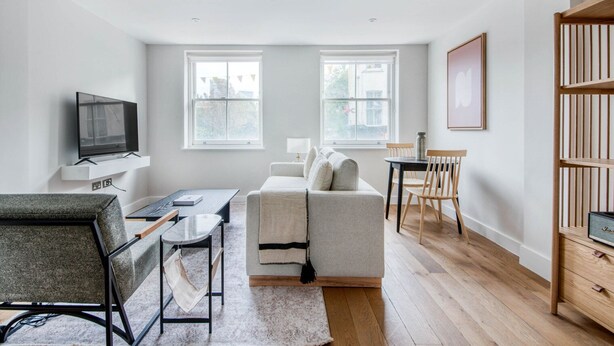 A modern living room with a sofa, a TV on a stand, a dining table with chairs, and a bookshelf. - Modern Waterloo 1BR w/ open plan on Lower Marsh, by Blueground (London)