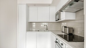 Una cocina moderna con armarios blancos, una campana extractora de acero inoxidable, un microondas y un tostador.