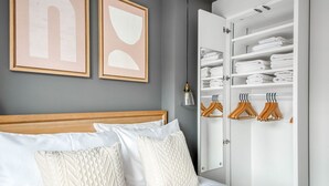 A bedroom with a bed, two framed artworks, a wardrobe with hangers, and a mirror. - Modern Waterloo 2BR open plan with Balcony on Lower Marsh, by Blueground (London)