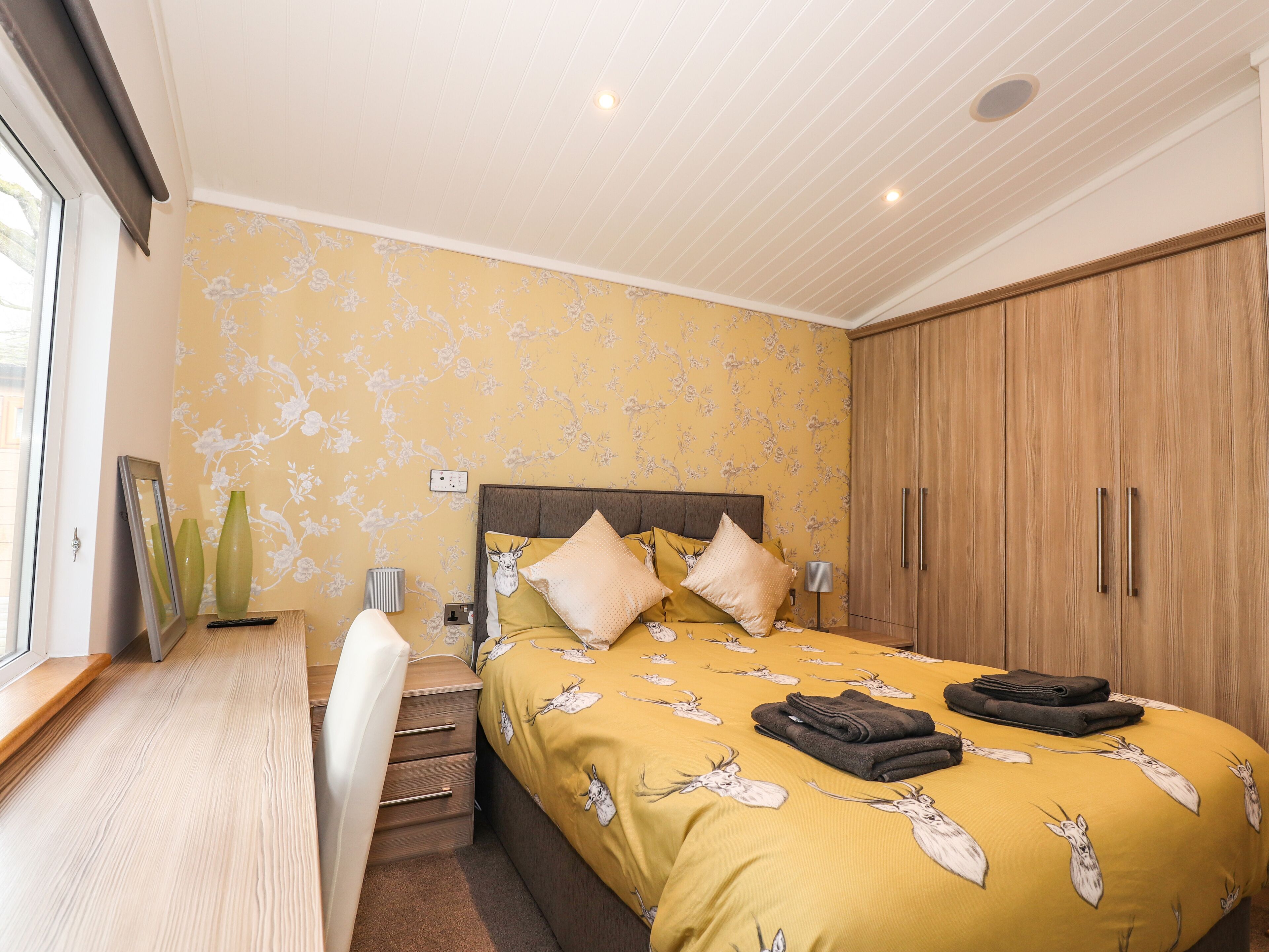 Ein Schlafzimmer mit einem Bett, einem Holzschrank und einem Schreibtisch mit Stuhl.