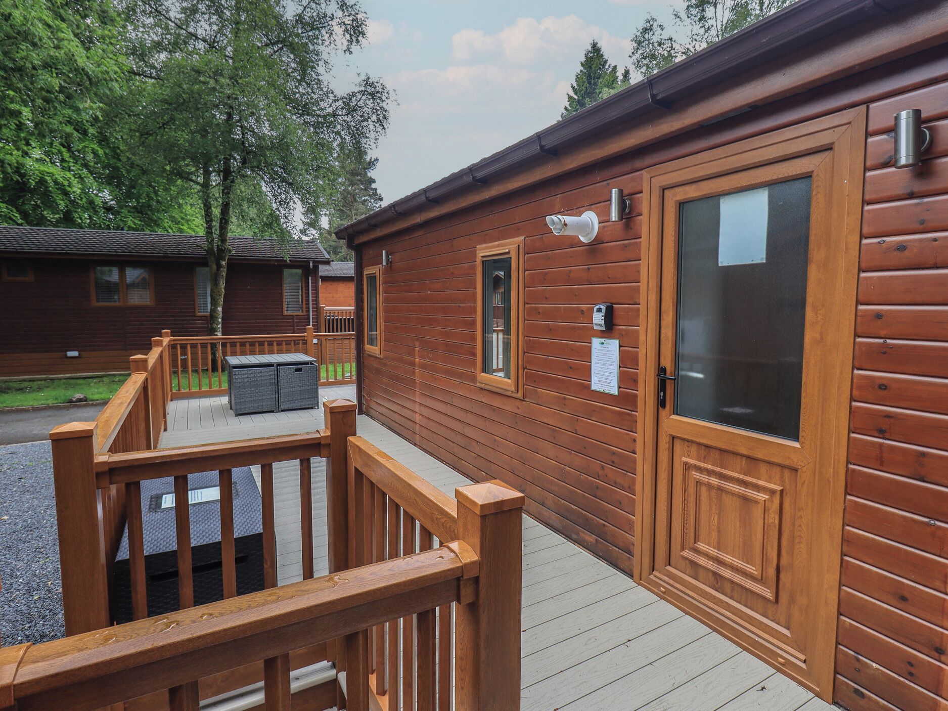 Une cabane en bois avec une terrasse, une porte et une fenêtre.
