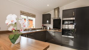 A modern kitchen with dark cabinets, stainless steel appliances, and a wooden countertop. - Ridgway Lodge (Windermere)