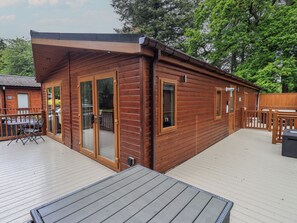 A wooden cabin with a deck, a sliding glass door, and a small outdoor seating area.