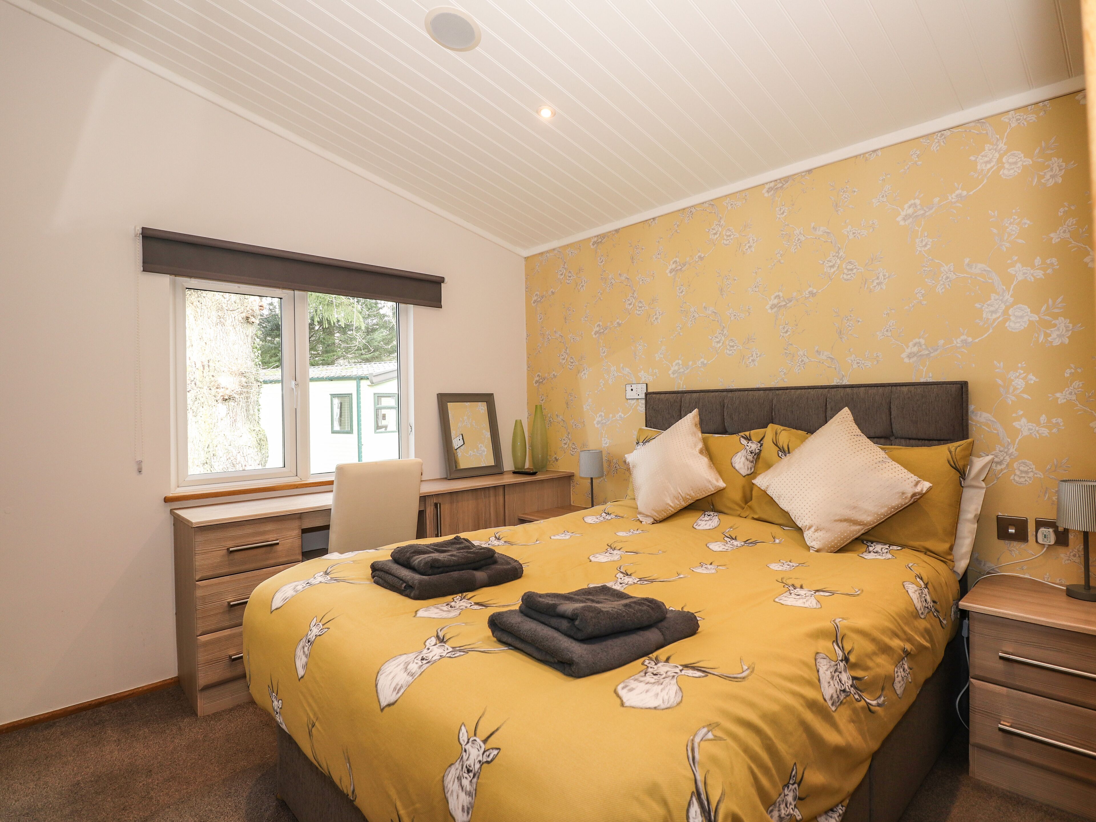 A bedroom with a bed, a desk, a chair, and a window.