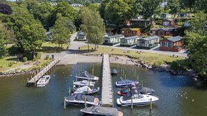 A marina with several boats docked, a wooden pier, and a row of houses in the background. - Buttermere Lodge (Windermere)