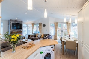 A modern living room with a sofa, dining table, and a washing machine.